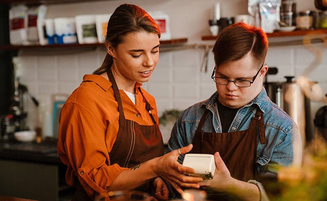 Two restaurant staff in aprons examine a tannsaction is progress on card payment terminal.