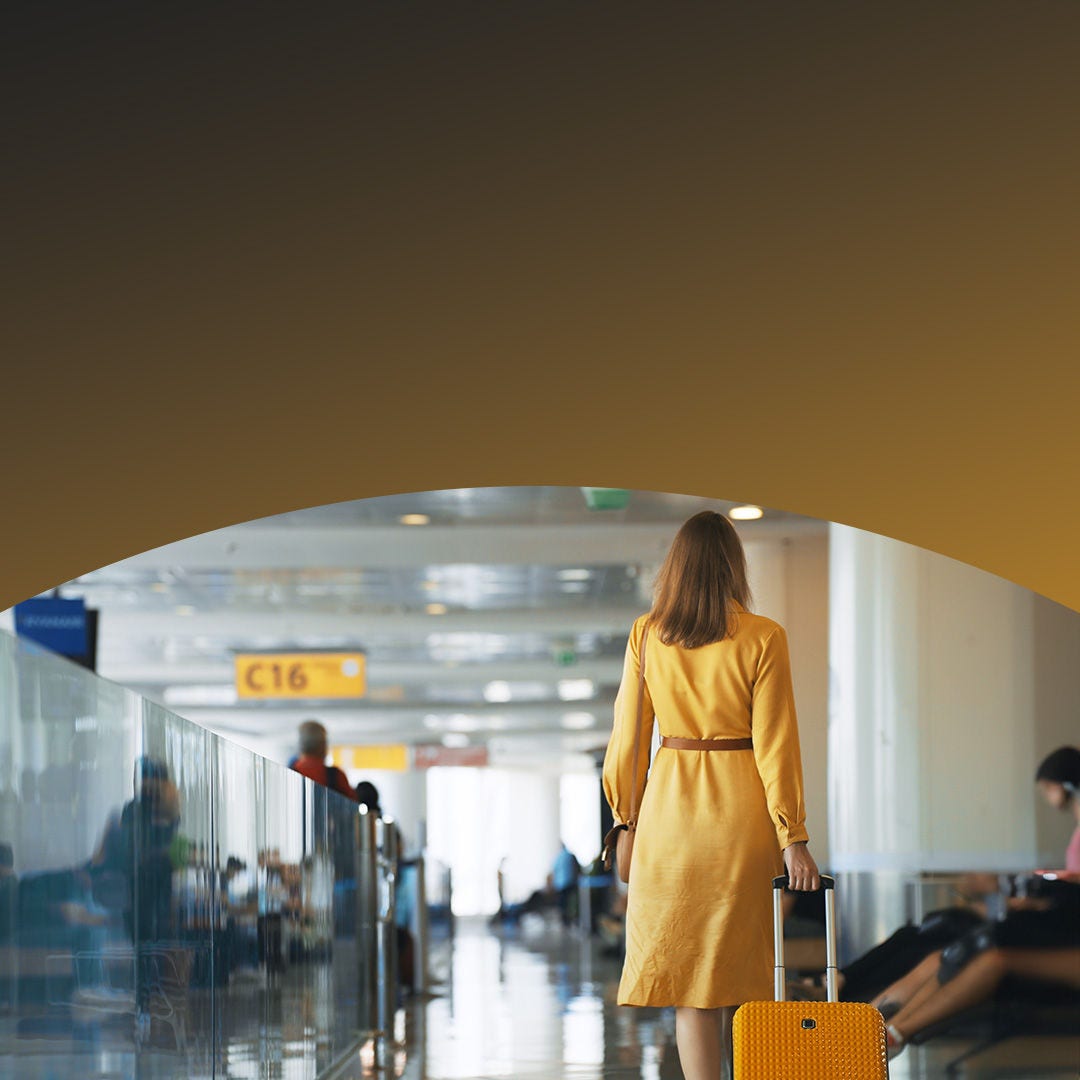 Woman walking through an airport with luggage. 