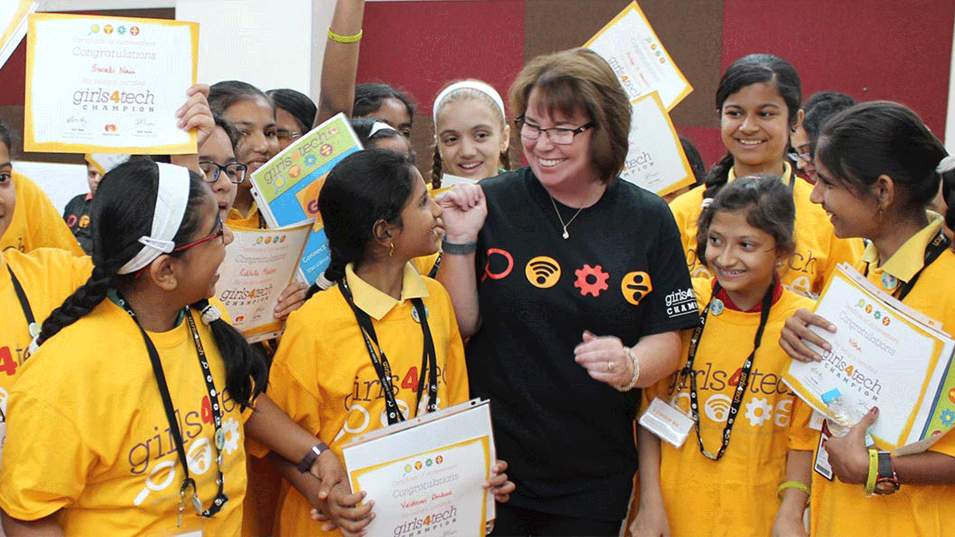 A teacher surrounded by her students holding up signs.