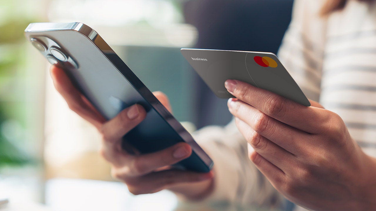 Woman's hand holding a credit-card, using smartphone for shopping online.