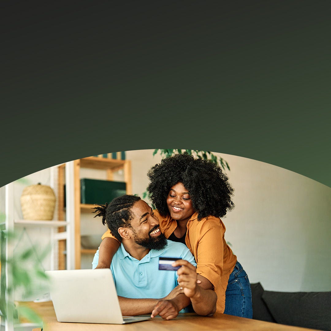 Couple sharing a joyful moment while making an online payment with Mastercard on a laptop.