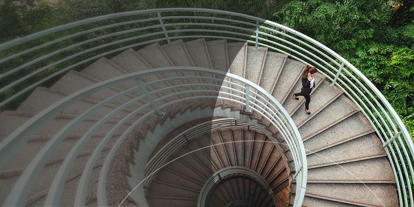 A person descends a spiral staircase, showcasing the elegant curves of the stairs and the surrounding architecture.
