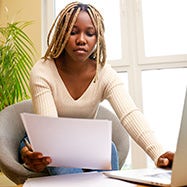 Woman working on her laptop while reviewing bills.